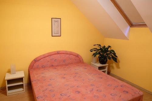 ジュラにあるVár-Torony Apartmanのピンクベッドと植物のあるベッドルーム1室が備わります。