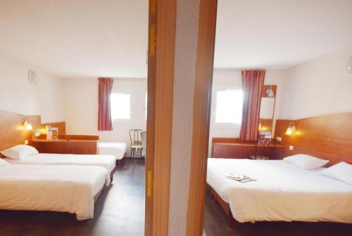 two beds in a hotel room with two windows at Brit Hotel Reims La Pompelle in Reims