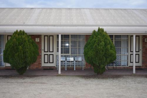 two trees in front of a building with a table and chairs at Kerang Motel in Kerang