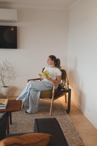 a woman sitting in a chair in a living room at Penny Shack - Incredible sea views and just two minutes to the ferry in Penneshaw