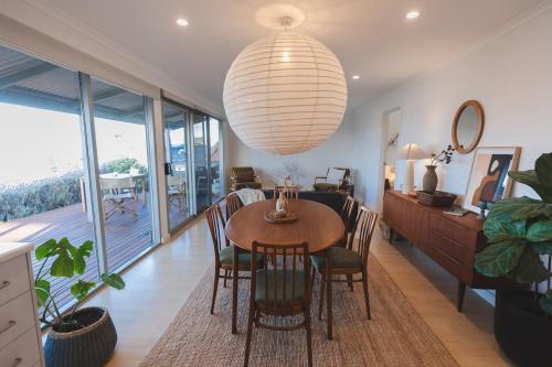 a dining room with a table and chairs and a large light fixture at Penny Shack - Incredible sea views and just two minutes to the ferry in Penneshaw