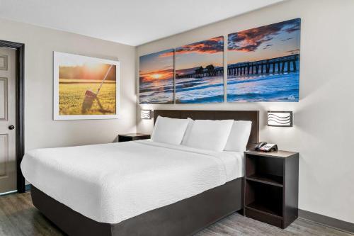 a hotel room with a bed and paintings on the wall at Days Inn by Wyndham Spartanburg in Spartanburg