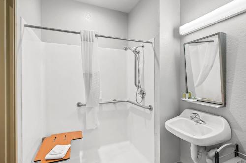 a white bathroom with a sink and a shower at Microtel Inn & Suites by Wyndham Searcy in Searcy