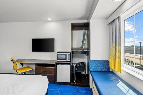 a hotel room with a bed and a desk and a tv at Microtel Inn & Suites by Wyndham Searcy in Searcy