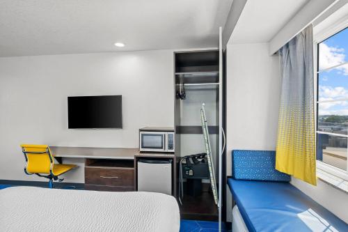 a room with a bed and a desk and a tv at Microtel Inn & Suites by Wyndham Searcy in Searcy