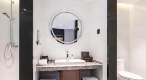 a white bathroom with a sink and a mirror at Yitel Collection Lianyungang High-speed Railway Station Suning Plaza in Lianyungang