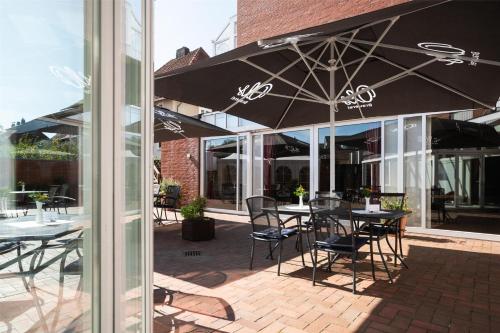 a patio with tables and chairs under an umbrella at Best Western Hotel Heide in Oldenburg