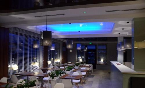 a restaurant with tables and chairs and a blue light at Hotel Pauza in Radzyń Podlaski