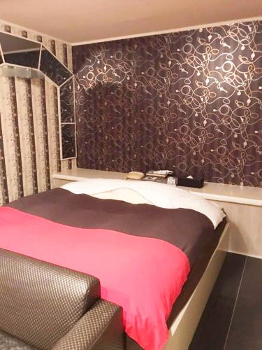 a bedroom with a pink bed and a black wall at 夢街道 in Fukuyama