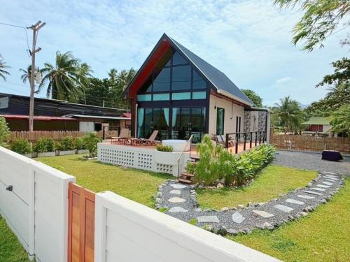 a house with a black roof and a white fence at GoldenHour House- Seaview & Sunset in Koh Phangan