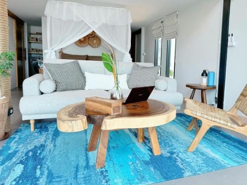 a living room with a couch and a table with a laptop at GoldenHour House- Seaview & Sunset in Koh Phangan