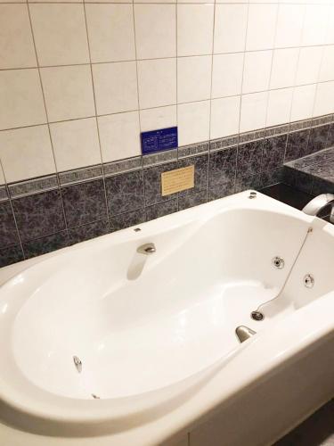 a white bath tub in a bathroom with a tile wall at 夢街道 in Fukuyama