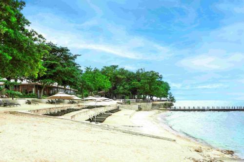 a beach with umbrellas and chairs and the ocean at Savoy Hotel Mactan Cebu near Newtown Beach in Mactan