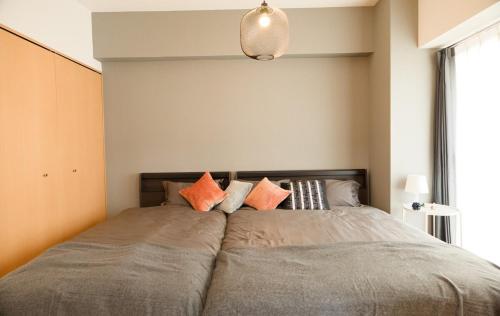 a bedroom with a large bed with orange pillows at SN4B ノワールネスト 都会のシックな隠れ家 Noir Nest urban chic retreat in Nagoya
