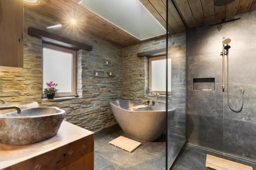 y baño con bañera grande y ducha acristalada. en Stone Cottage, en Arrowtown