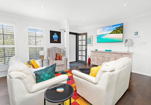 a living room with two white chairs and a table at Seaside Sanctuary in Kiama