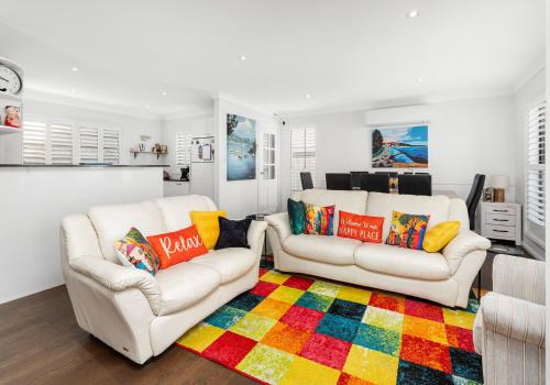 a living room with two white couches and a colorful rug at Seaside Sanctuary in Kiama
