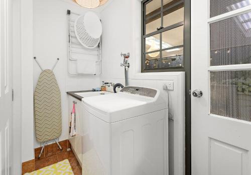 a small bathroom with a sink and a washing machine at Seaside Sanctuary in Kiama