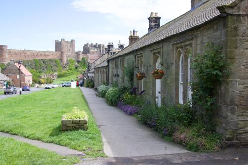 an old building with flowers on the side of a street at Pintail Apartment Bamburgh in Bamburgh