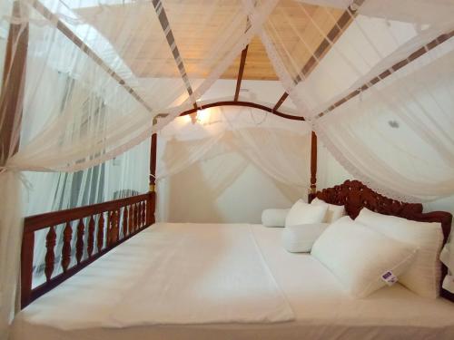 a bedroom with a canopy bed with white pillows at Villa Thisansa in Mirissa