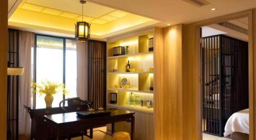 a room with a desk and a bedroom with a window at Yuan Culture Hotel Shenzhen World Shajing in Shenzhen