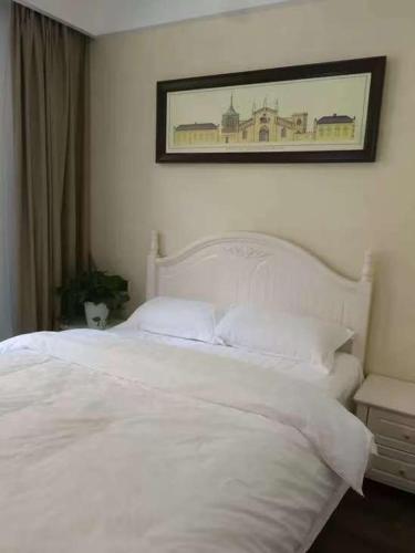 a bedroom with a white bed with a picture on the wall at 笑涡SmileNest Downtown Luxury Suite for 2-10 Guests, Zhangjiajie Attraction Ticket Service, Ideal for Couples, Families & Groups in Zhangjiajie