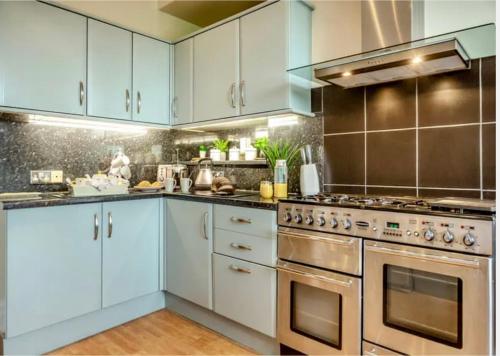 a kitchen with white cabinets and stainless steel appliances at Jack's House in Tywyn