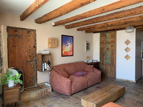 a living room with a brown couch and wooden ceilings at Studio indépendant tout équipé in Montpeyroux