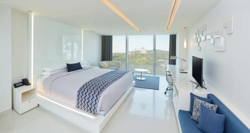 a white bedroom with a large bed and a tv at Vista Walkerhill Seoul - formerly W Seoul in Seoul