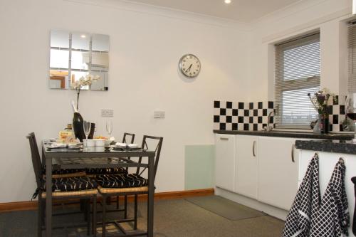 a kitchen with a table and a clock on the wall at Pintail Apartment Bamburgh in Bamburgh