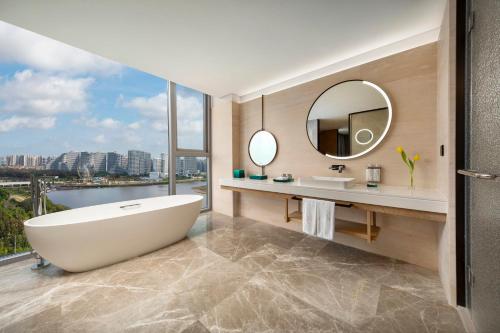 a bathroom with a tub and a large mirror at HUALUXE Beihai Silver Beach Resort by IHG in Beihai