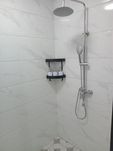 a white bathroom with a shower with a shower head at Vailoa 1bedroom, 5 min to Apia, AC, Wi-fi, kitchen in Apia