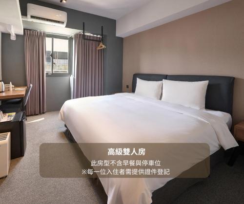 a bedroom with a large white bed and a desk at Doudian DDiNN Hotel in Taichung