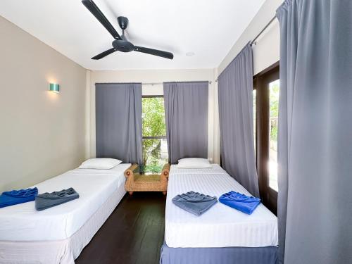 two beds in a room with a window at Seetanu Bungalows in Srithanu