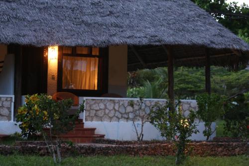 a small house with a thatch roof and a window at Hotel Club Dongwe in Pingwe