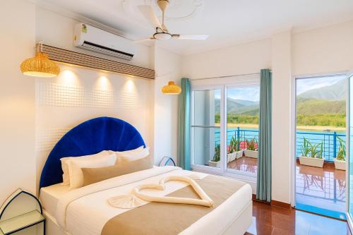 a bedroom with a bed with a blue headboard and a balcony at The Neeraj Ganga Cottages in Rishīkesh