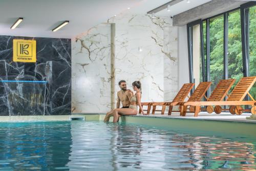 a man and woman sitting next to a swimming pool at Kutaisi Inn in Kutaisi