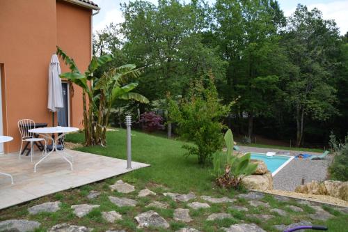 a backyard with a table and a pool at La Colline des Endrevies in Saint-André-dʼAllas