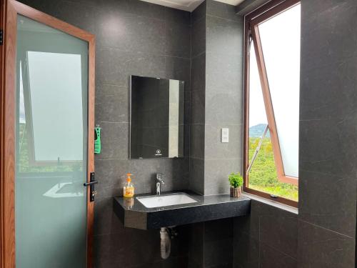 Bien HoにあるPleiku Adventures Homestayの洗面台と鏡と窓のあるバスルーム