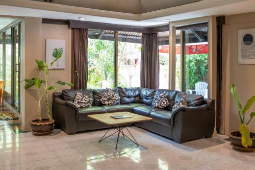 a living room with a leather couch and a table at Seetanu Bungalows in Srithanu