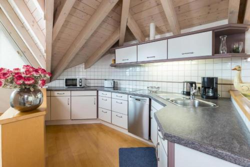 a kitchen with white cabinets and a vase of flowers at Gästehaus Anita in Gailingen