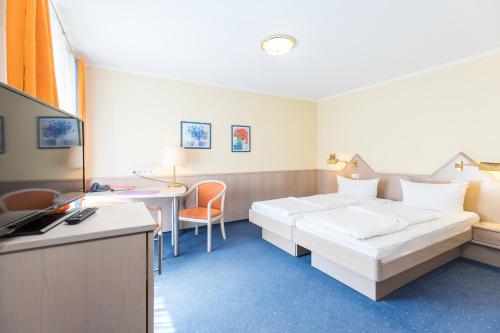 a hotel room with two beds and a desk at Gästehaus Anita in Gailingen