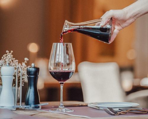 a person pouring wine into a glass on a table at Hotel Villa Medici in Bad Schonborn