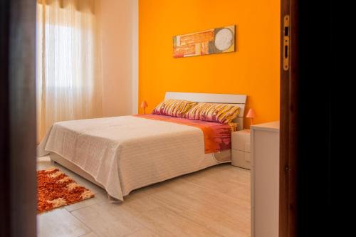 um quarto com uma cama com uma parede laranja em Licata Mare em Trapani