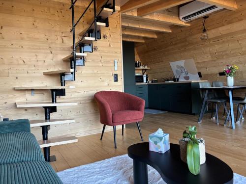 un soggiorno con una sedia rossa e un tavolo di Chalet VercoréA 56 m2 pour 4 personnes au Domaine CollinéA SPA Privatif a Bathernay