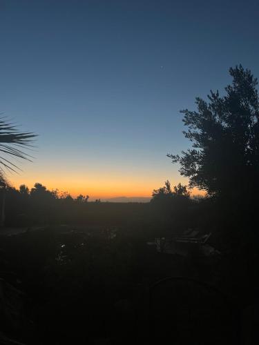a sunset in the sky with trees in the foreground at Tigmmi N Usnful in Amizmiz