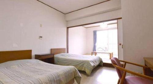 a bedroom with two beds and a window at Petit Hotel Key West Club in Naha