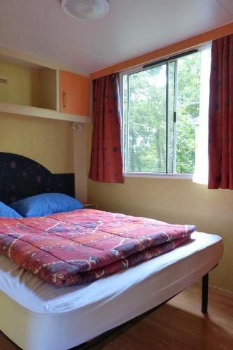 a bed sitting in a bedroom with a window at Chateau-camping la Grange Fort, 63500 Les Pradeaux in Les Pradeaux