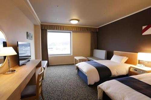 a hotel room with two beds and a television at Green Hill Hotel Onomichi in Onomichi