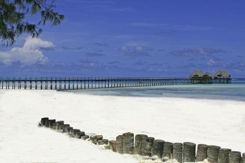 a beach with a pier in the water at Hotel Club Dongwe in Pingwe